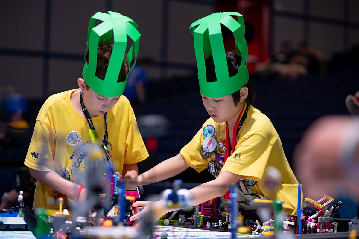 Two FIRST LEGO League students working on their robot at FIRST Championship.