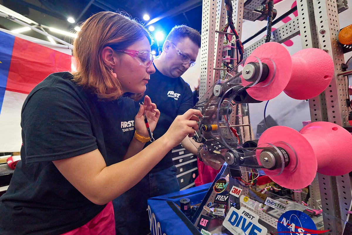 FIRST Robotics Competition student working on their robot at FIRST Championship with the help of a FIRST mentor.
