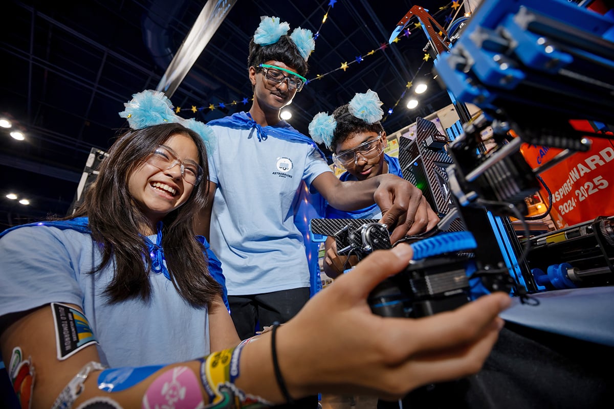 Three FIRST Tech Challenge students working on their robot at FIRST Championship