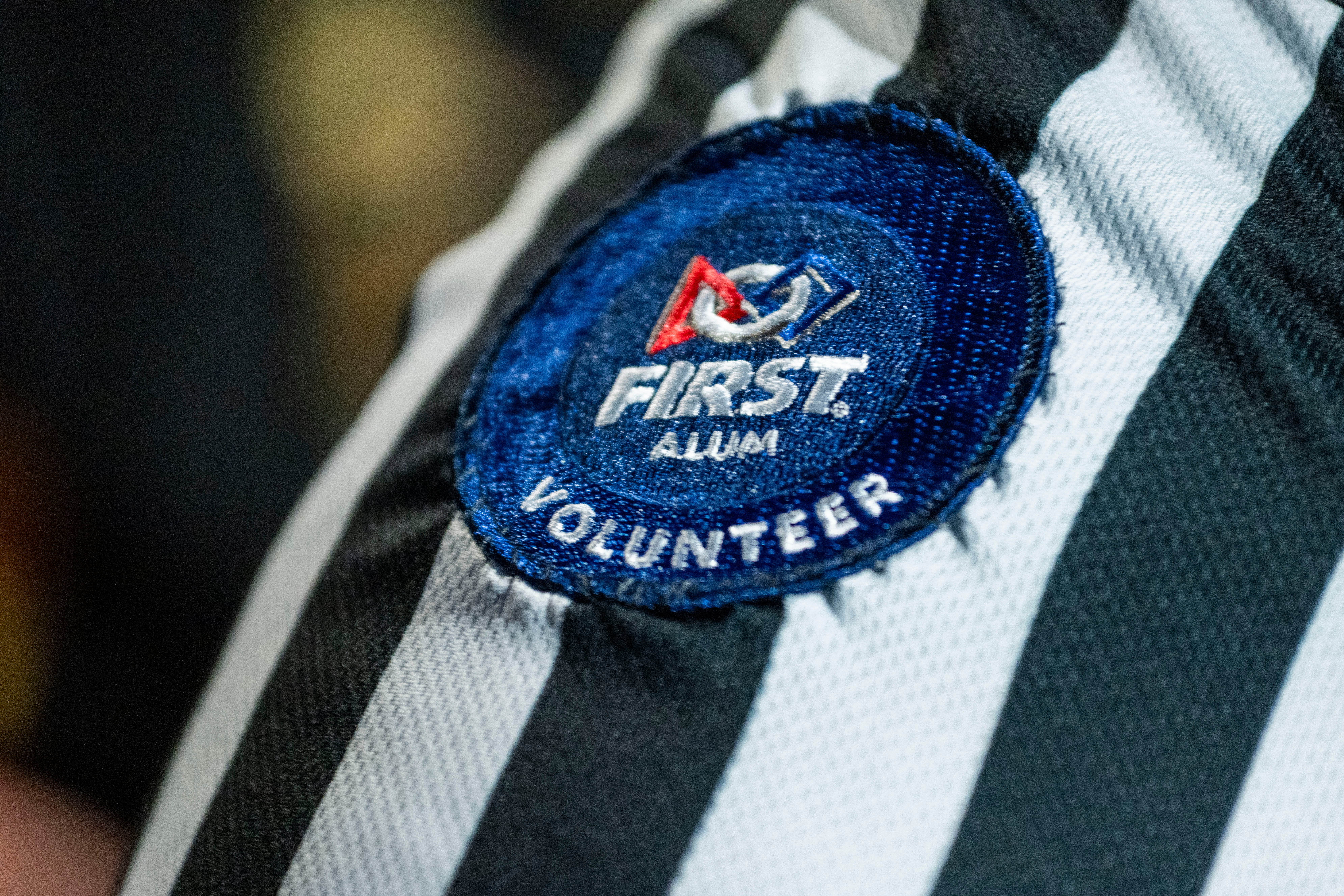 close up of FIRST alumni and FIRST volunteer badge